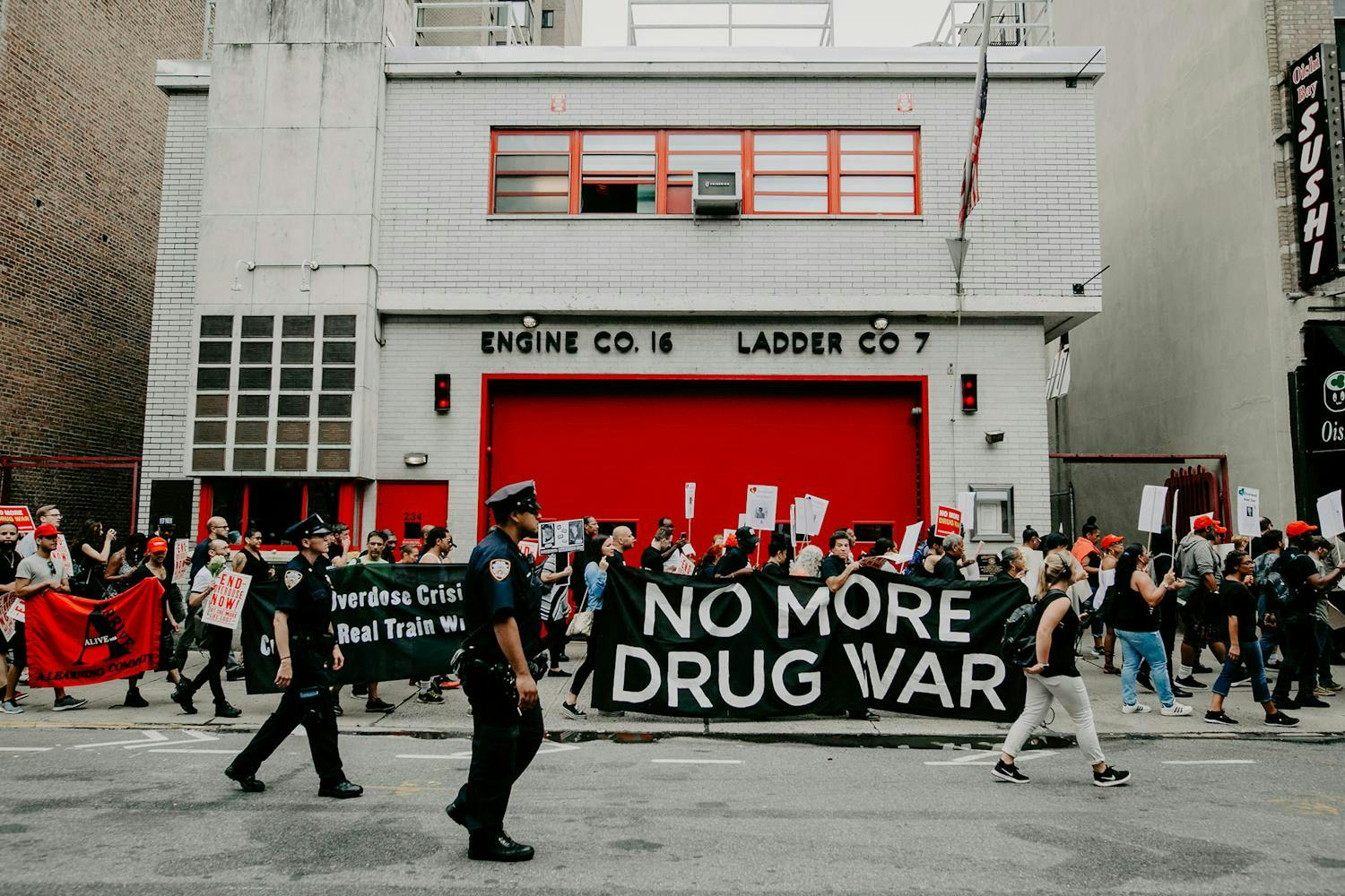 People at a rally holding a sign that says "no more drug war"